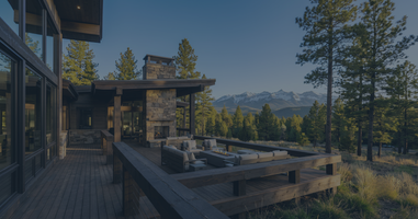 A spacious luxury mountain home with a large wooden deck overlooking a pine forest and the San Juan Mountains in Pagosa Springs, Colorado, illustrating the value of acreage over urban density.